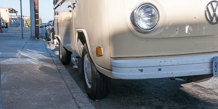 Vintage Volkswagen bus parked close to curb on city street.