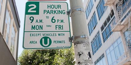 Green and white parking sign showing 2-hour parking limit Monday through Friday, 9 A.M. to 6 P.M., except for vehicles with Area U permits.
