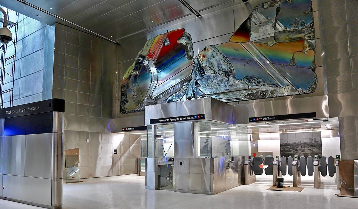 Colorful artwork above the fare gates at Yerba Buena/Moscone Station made of mirrors, paint, engraved glass, sheet metal and gravel.