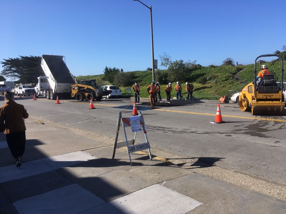 Construction crews pour asphalt for a speed hump on Lower Great Highway.