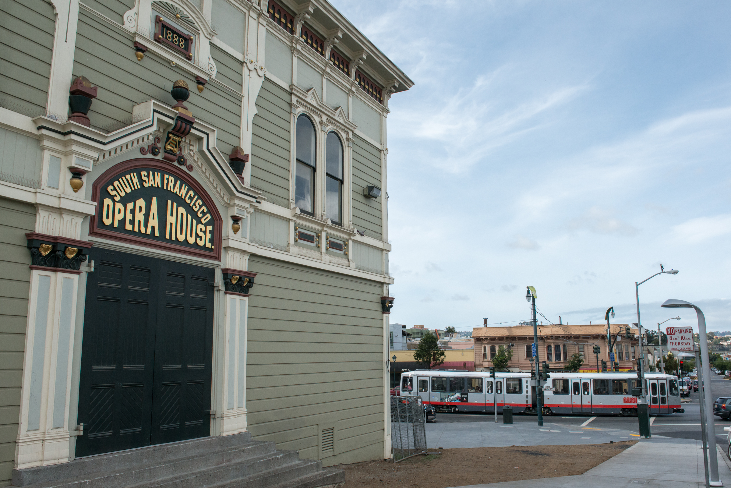 Facade of the Bayview Opera House with a Muni T Third  light rail vehicle running in the background