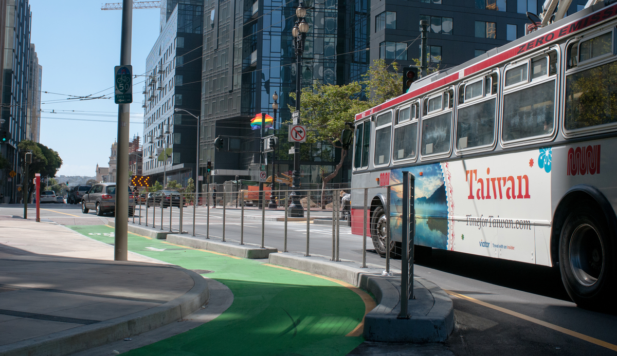 Muni bus travels south on Polk Street with the green painted Polk St. contraflow bike lane in the foreground.
