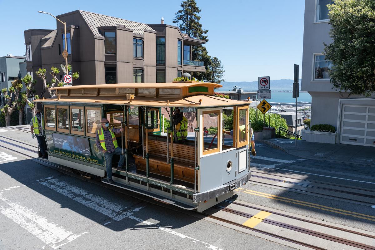 Photo of Powell and Hyde Cable Car with three staff members wearing masks