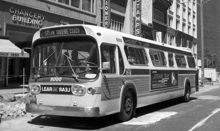 Black and white photo showing a GMC brand bus on Market Street near Sansome on August 23, 1972.  This bus is outfitted with a Lear steam turbine engine for testing by Muni.