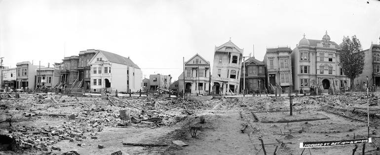 Black and white photo showing damaged houses, leaning and sinking into the ground on South Van Ness and 18th St, taken May 9, 1906 after great earthquake and fire.