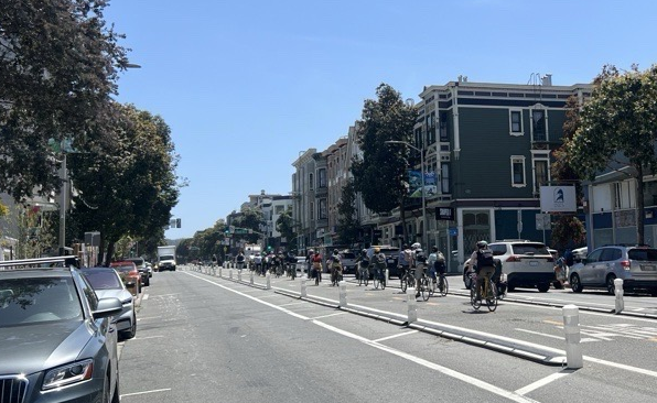 La gente anda en bicicleta por el carril bici que discurre por el centro de Valencia Street.