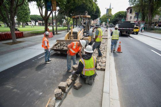 In North Beach on Columbus Avenue, work crews from Sustainable Streets are landscaping with cobblestones within the median.