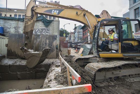 A worker uses an excavator to remove debris from the spoils pit.