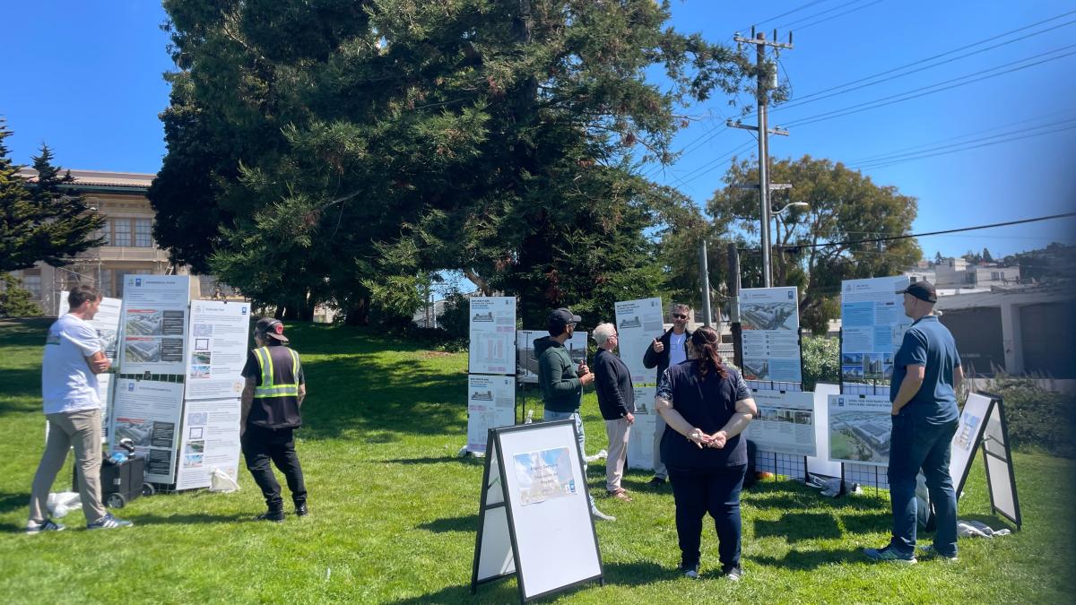 people on a grassy hill looking at informational signage