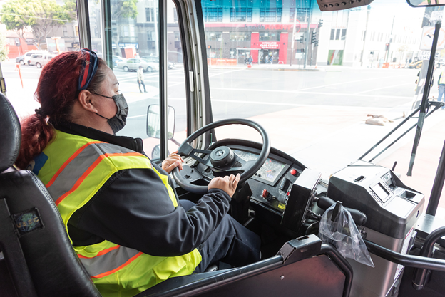 A Muni operator wearing a mask drives on the street.