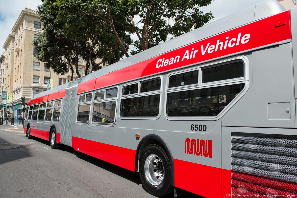 Red and silver articulated bus labeled "Clean Air Vehicle" with number 6500 parked on city street.