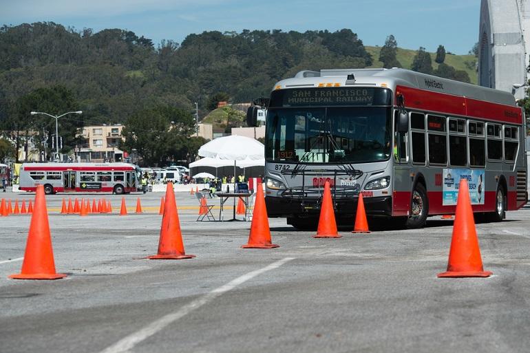 Muni bus navigating through orange safety cones during a driver roadeo competition.