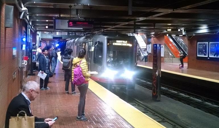 Passengers wait on a subway platform as a Muni train arrives at the station.