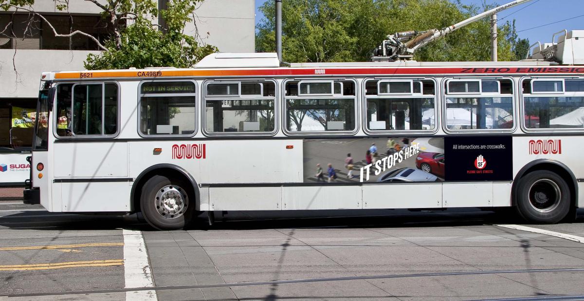 White Muni bus with "It Stops Here" safety advertisement on its side, parked on a city street.