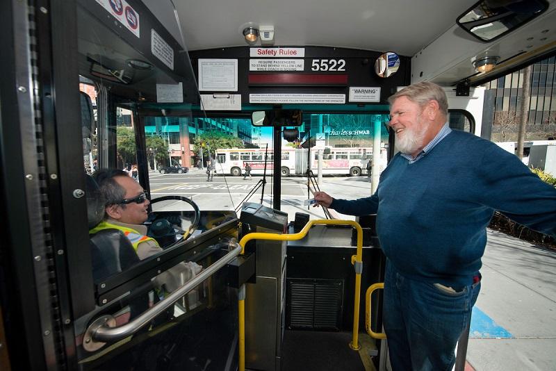 Muni bus operator at steering wheel greets passenger boarding bus 5522.