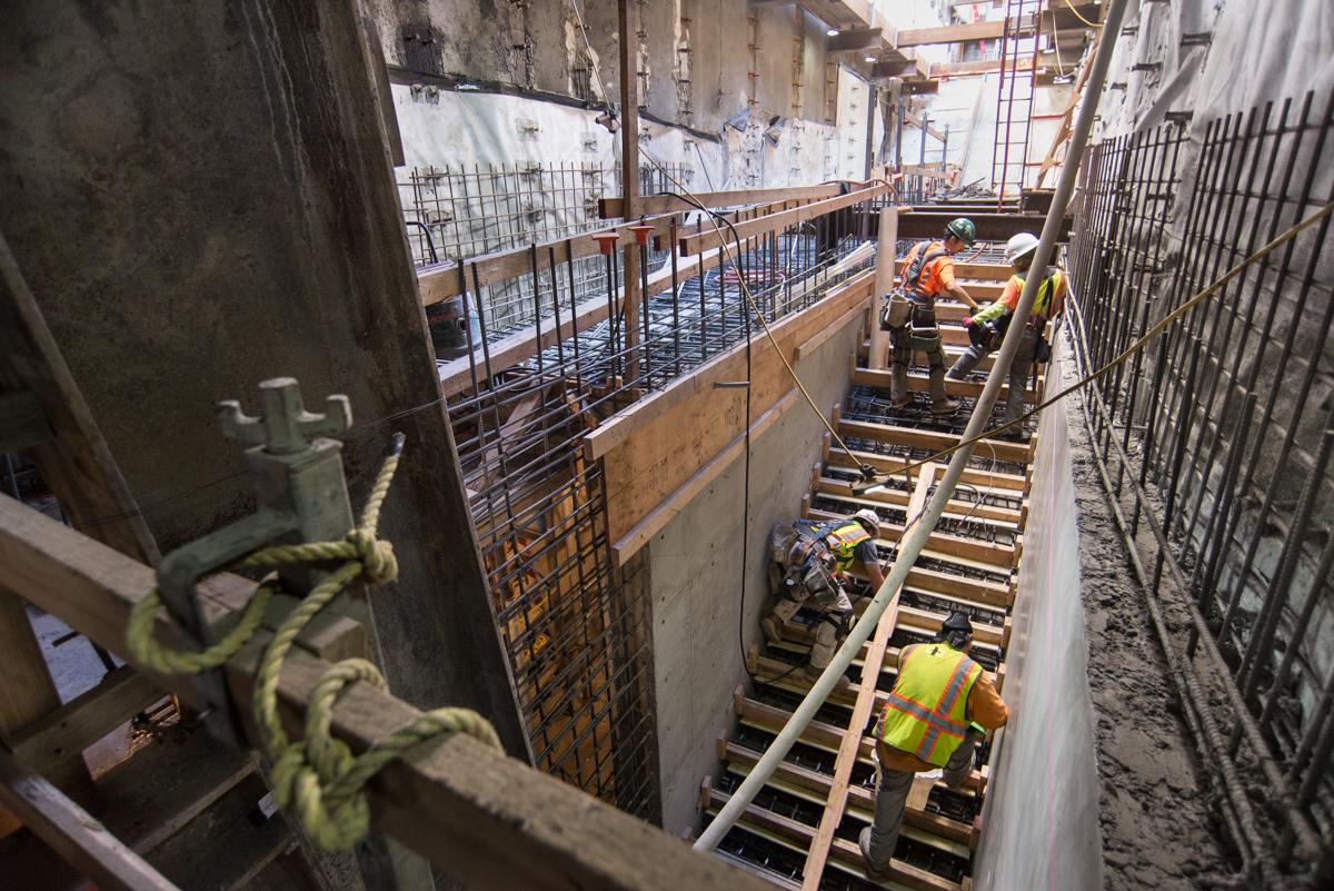 Construction workers install concrete forms for emergency egress staircase stairs at underground transit station.