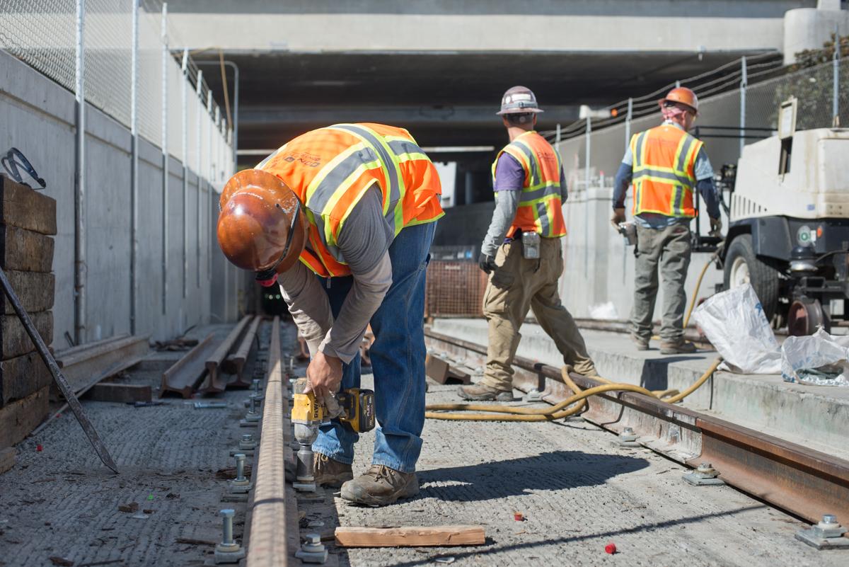 Construction workers install rail sections in subway tunnel portal near 4th and Bryant.