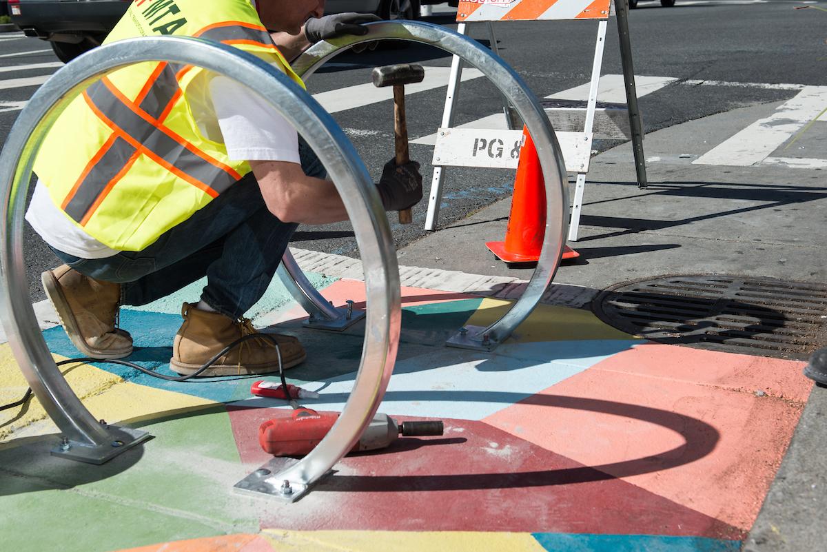 A Sign Shop installer lays down new bike racks.