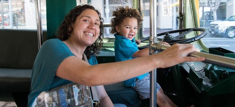 A child sitting in the operator's seat of a streetcar.