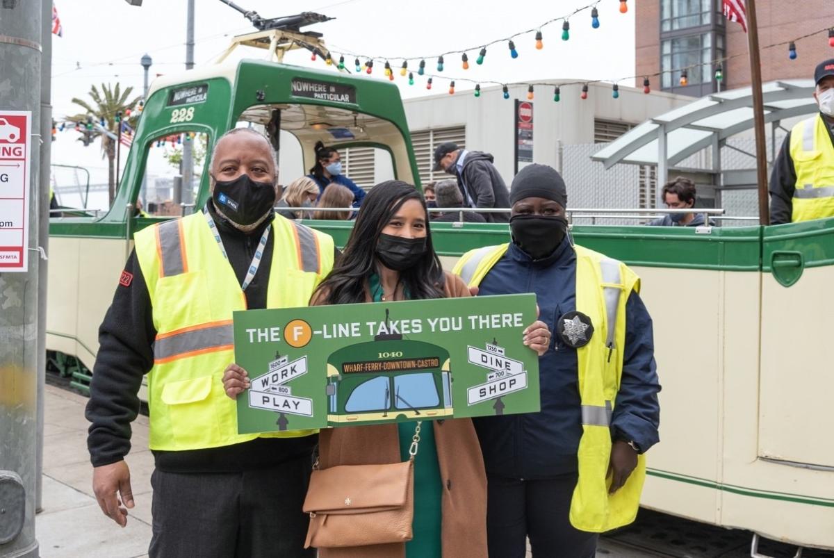 Photo of SFMTA staff holding "The F Line Takes You There" sign