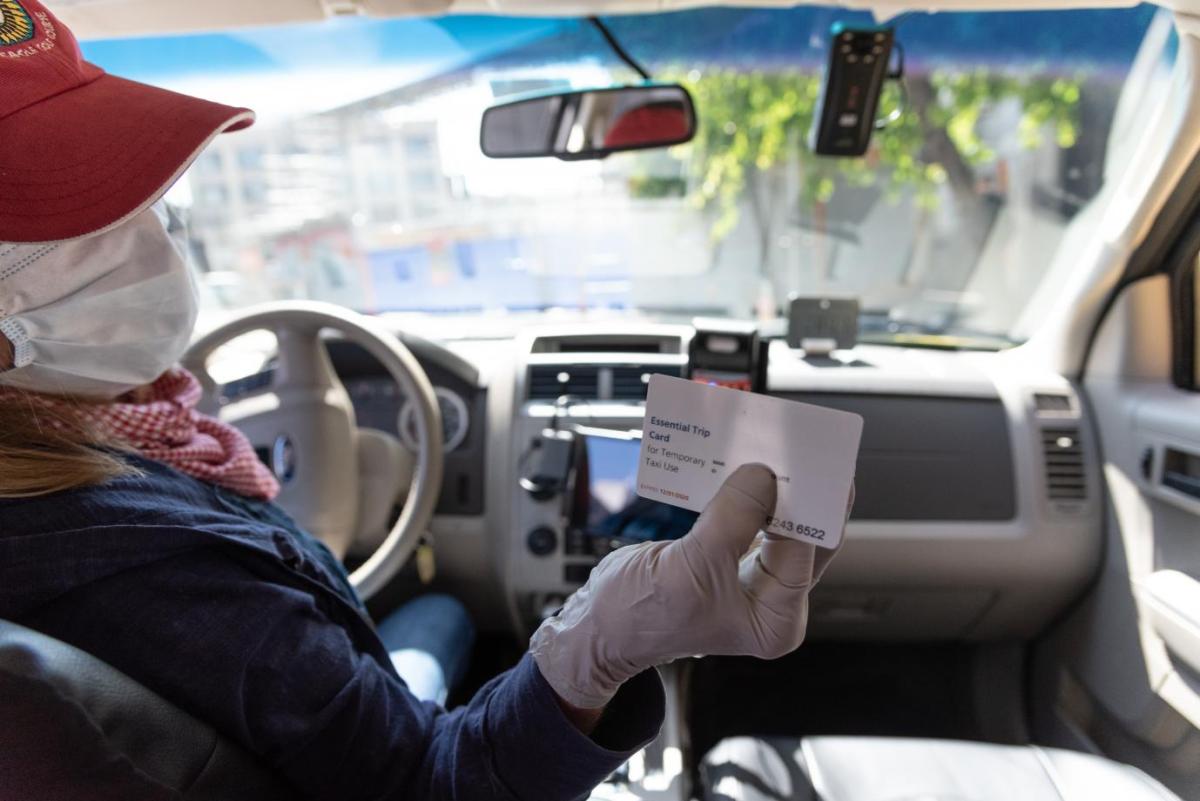 Image of taxi driver holding essential trip card