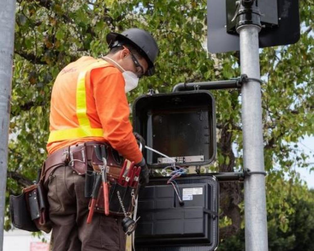 Photo of A crew member programming a pedestrian signal on a recently-installed traffic signal on Van Ness.