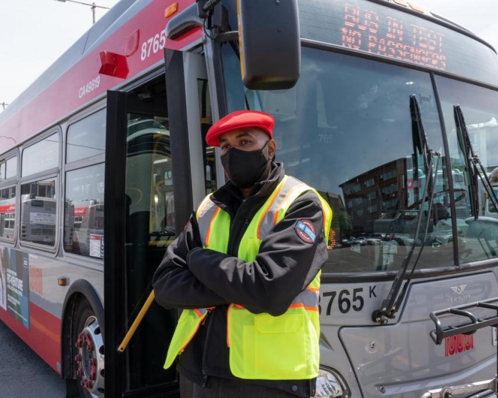 Operator standing in front of bus with open doors
