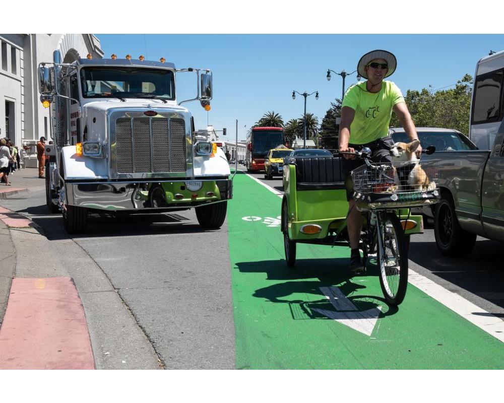 View of a pedicab driver riding in the northbound bike lane on The Embarcadero in front of Pier 35, looking south