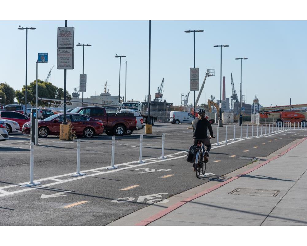 A bicyclist in a two-way protected bikeway buffered with plastic delineators
