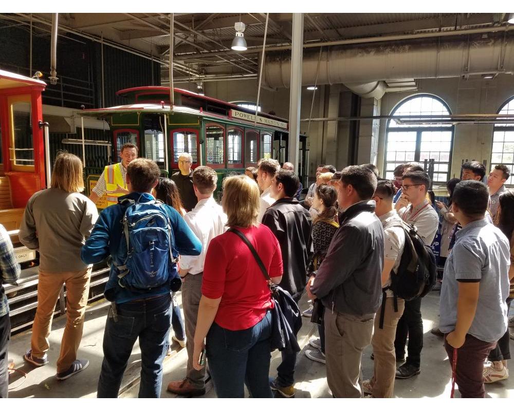 Photo of interns listening to presentation with cable car in background