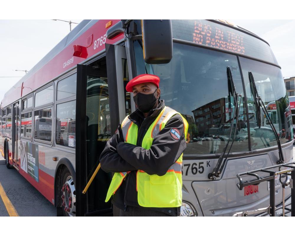 Operator standing in front of bus with open doors