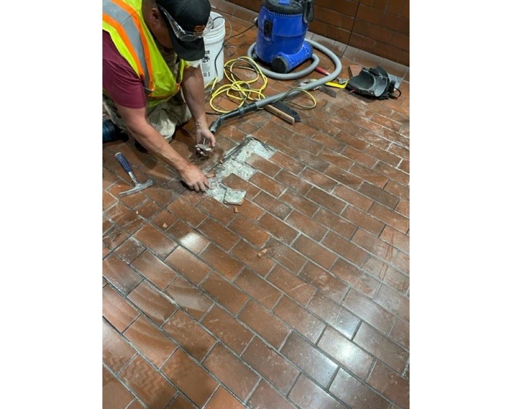 Dan Alger from mechanical system group replaces worn and broken floor tiles