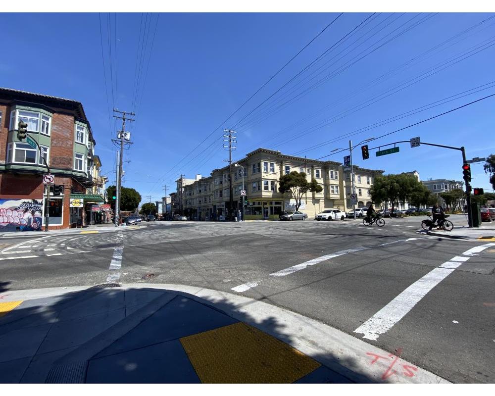 Intersection of Guerrero and 16th streets with cyclists and crossing in crosswalk. Car tire marks prevalent. 