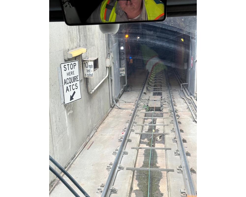 Muni Metro train tracks leading into tunnel opening with sign that says stop here acquire A.T.C.S.