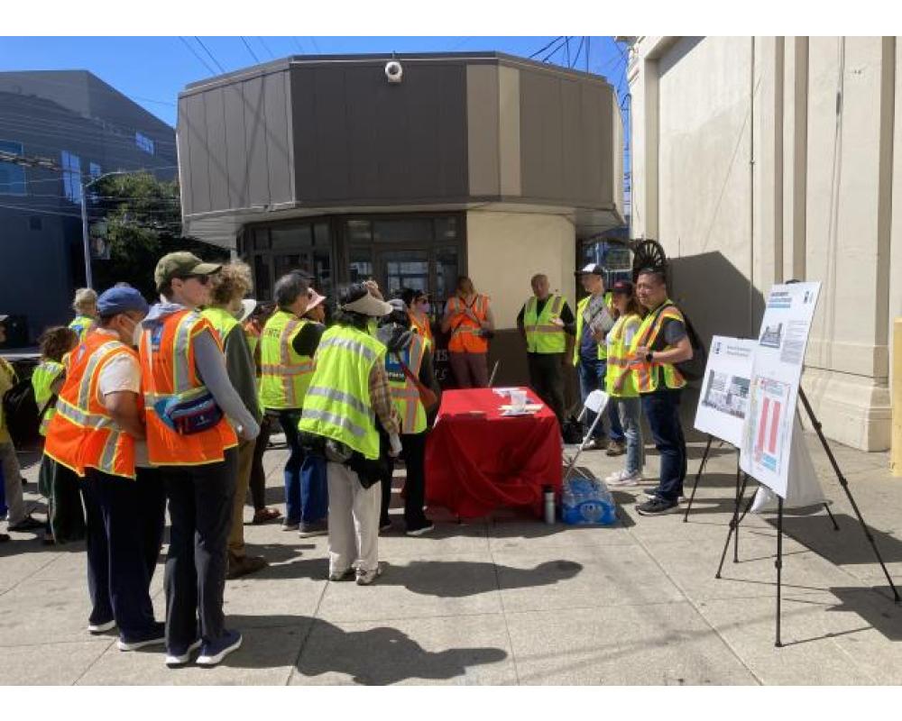 a group of people in safety vests are gathered outside a transit facility