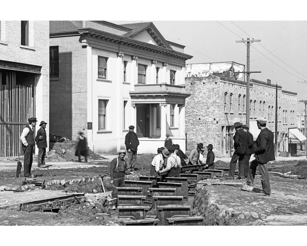 black and white photo of men working on rails in the street
