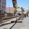 Another length of rail is lifted into place onto steel rollers to be moved north up 4th Street.