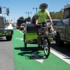 View of a pedicab driver riding in the northbound bike lane on The Embarcadero in front of Pier 35, looking south