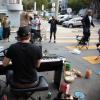 Community members on Page Slow Street stop and listen to a man playing piano in the street