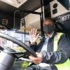 Operator waiving hello at the wheel of a bus