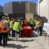 a group of people in safety vests are gathered outside a transit facility