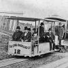 black and white photo of original cable train on clay street hill in 1873 with people on board.