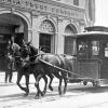 black and white photo of a horse-drawn streetcar in downtown san francisco in the late 1800s.