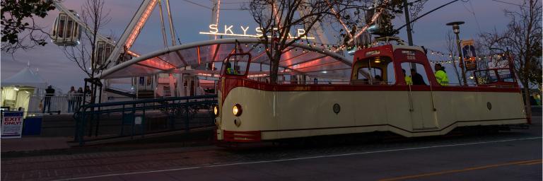 Open top "Boat" tram in Fishermans wharf at night in front of the carousel