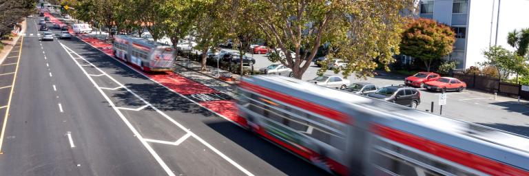 Two buses drive in new red transit lanes along Geary Boulevard in Japantown.