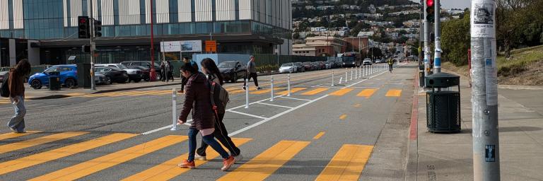 People crossing Frida Kahlo Way on foot.