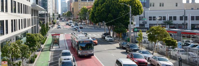 Bus driving down Mission Street in a red transit lane. 