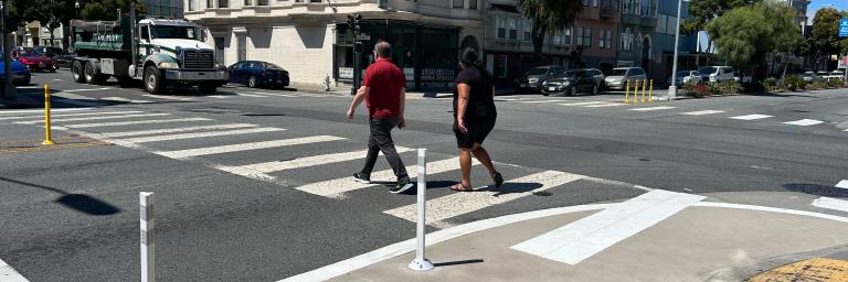 Two people walking across crosswalk