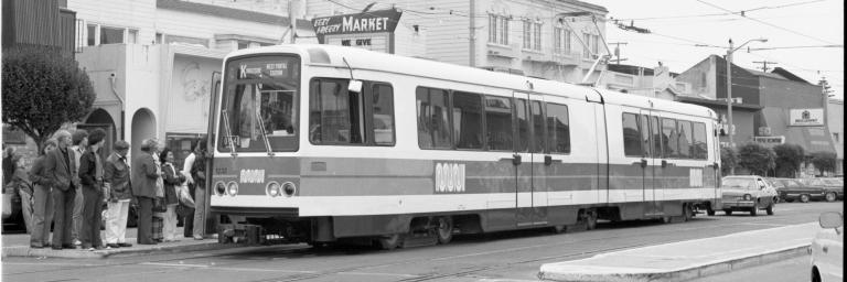 Black and White Image of the K Ingleside boarding a small group of passengers near Eezy Freezy Market.