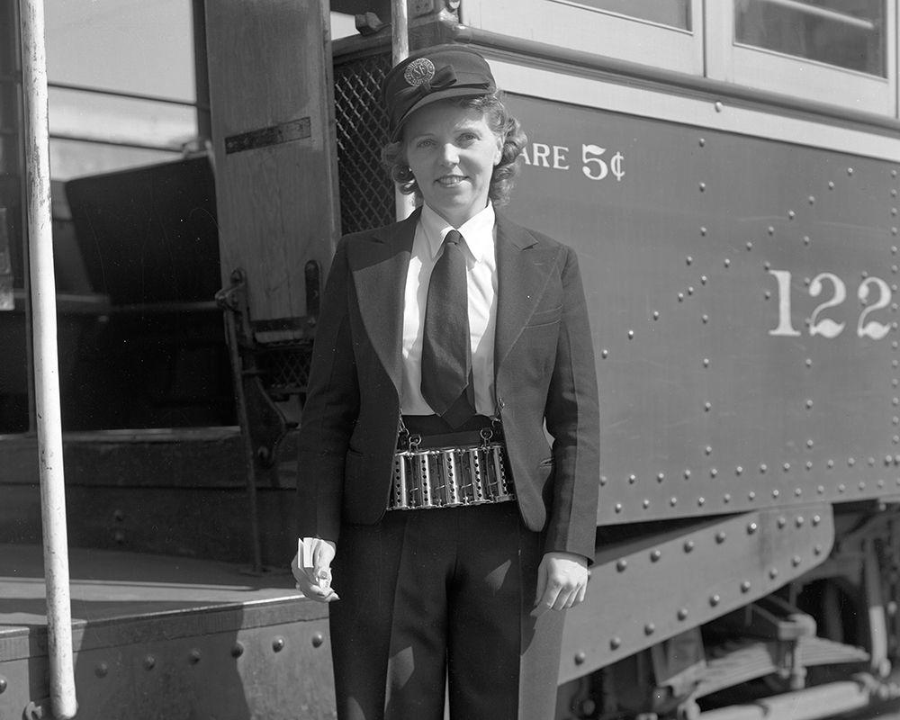 Person in uniform holding paper transfers and change maker standing in front of streetcar